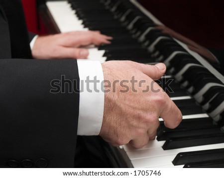 Stock photo of a closeup of a man's hands playing a piano.