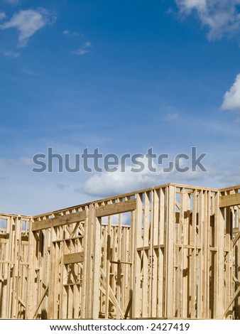 Stock photo of the wood frames of a new urban housing development under construction against a blue sky with white clouds.
