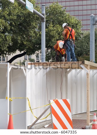 Construction crew working on a safety walkway outside of a building site.