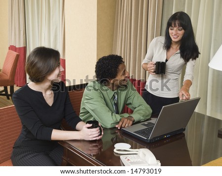 A business team cheerfully review good results on their laptop computer in a hotel room during a business trip.