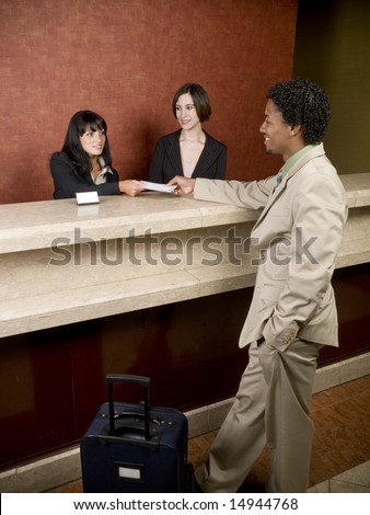 Hotel employees cheerfully welcome a guest.