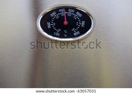 Closeup of the temperature gauge on an outdoor grill with the needle showing over 400 degrees.