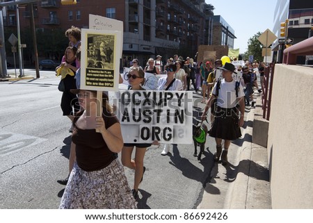 AUSTIN, TX - OCTOBER 15: An unidentified group of protesters carry signs along Lavaca Street during the \'Occupy Austin\' march to the Texas State Capitol on October 15, 2011 in Austin.
