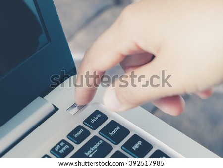 Close up image of finger pushing the power button on laptop computer.