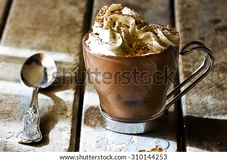 Cup of espresso coffee with chocolate and whipped cream on rustic wooden table