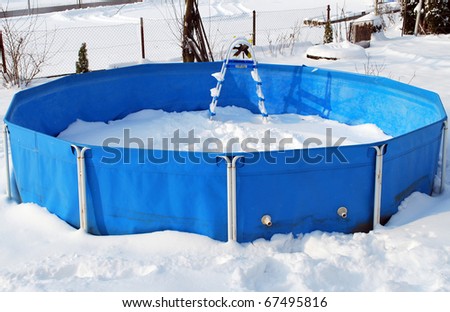 Abandoned swimming pool at winter, surrounded with snow