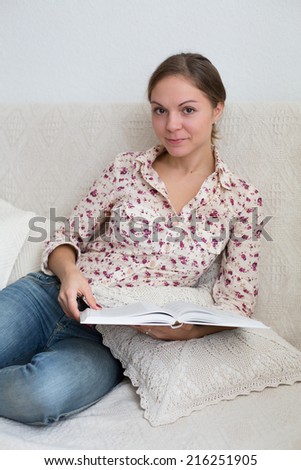 Portrait of woman 20-25 years old sitting at home with book in her hands