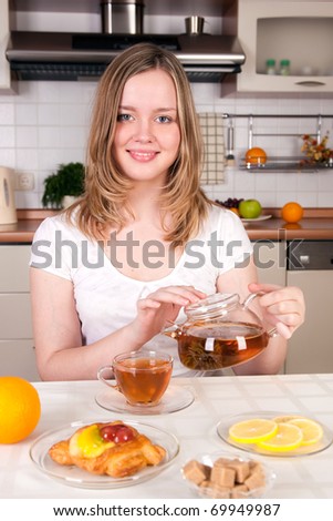 Cheerful young woman in kitchen at morning breakfast