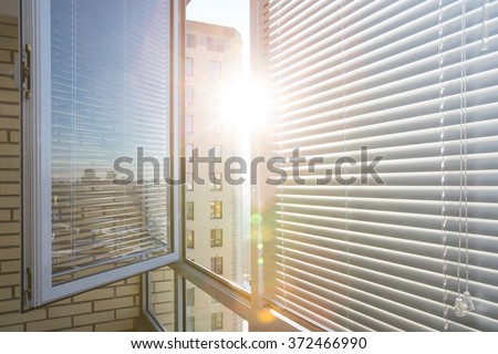 Opened window on sunny day with horizontal plastic blinds