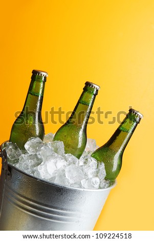 Three Green Beer Bottles in Ice Bucket with Condensation