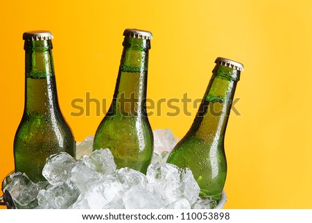 Three Green Beer Bottles in Ice Bucket with Condensation