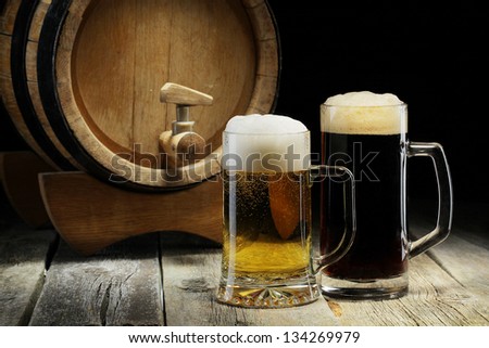 Lager and dark beer on the old wooden background with keg or barrel of beer.