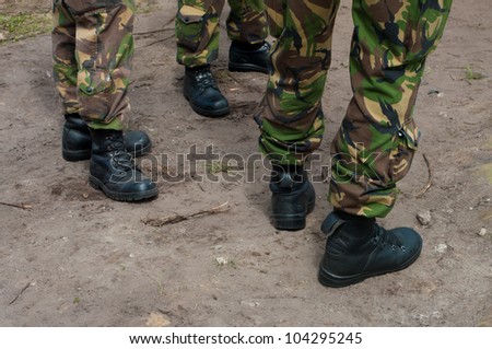 three pair of feet wearing uniforms and soldier boots