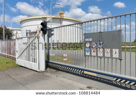 metal gate in front of an area with oil storage tanks in Amsterdam harbor