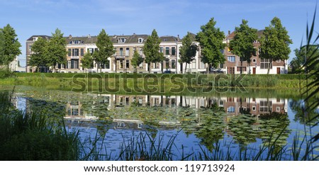 row of white residential houses reflected in a canal