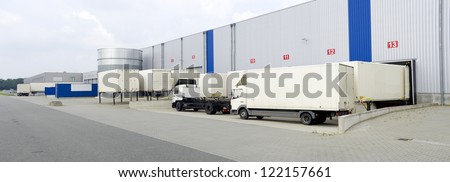 modern warehouse with containers and trucks in front