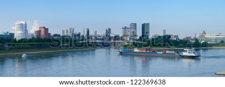 DUSSELDORF, GERMANY - AUGUST 11: Container ship on august 11, 2012 in Dusseldorf, Germany. As harbor lost its importance, nowadays the area itself contains some spectacular post-modern architecture.