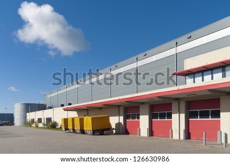 Large Warehouse With Red Loading Docks And Several Trailers For Rent