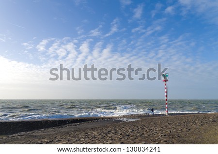 man watching the waves next to a small light beacon at the North Sea in netherlands