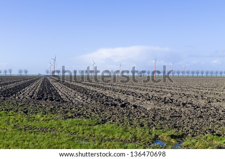 plowed field with a windmill farm in the background in Almere, Netherlands