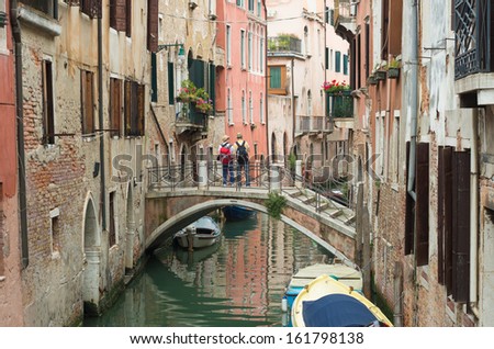 VENICE, ITALY - MAY 30: Two unknown tourists on a bridge on may 30, 2013 in Venice, Italy. Venice is one of the world\'s most popular tourist destinations with 21 million visitors each year.