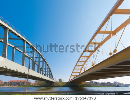 railroad bridge and yellow arch bridge in Utrecht, netherlands. The yellow Hogeweide Bridge is a steel arch bridge over the Amsterdam-Rhine Canal