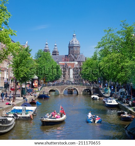 AMSTERDAM - MAY 18, 2014: Unknown people in a boat on an amsterdam canal. Amsterdam counts 165 canals with a total length of 100 km.
