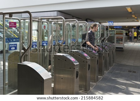 AMSTERDAM - JUNE 7, 2014: Unknown man passing automatic railway station gates for checking in or out