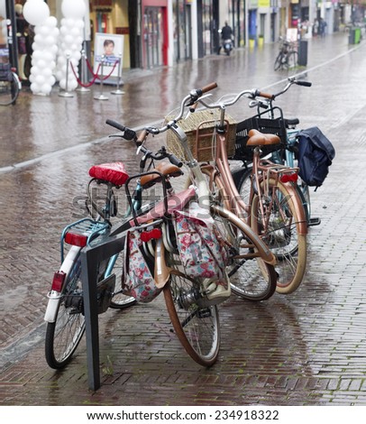 parked bicycles in a shopping street during heavy rain