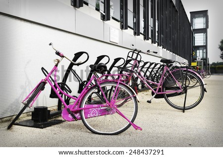 two pink bicycles parked outside a train station
