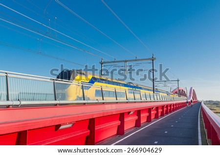 train passing the new red railroad bridge over the IJssel river in the Netherlands