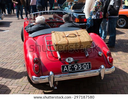 OLDENZAAL, NETHERLANDS - APRIL 27, 2015: Red oldtimer car with unknown people during the 14th orange tour. This annual tour takes places during the king\'s birthday celebrations, a national holiday.