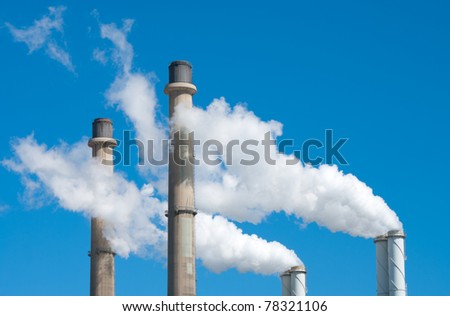smoking chimneys from a power plant against a blue sky