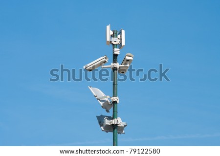 security cameras and floodlights mounted high on a pole to oversee an industrial area