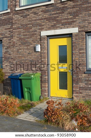 yellow front door and a blue and green trash can for separate trash