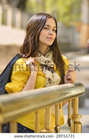 beautiful young woman in yellow blouse stands on the street