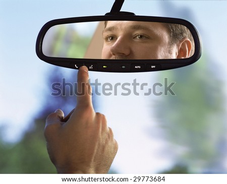 man sits on driver\'s seat and Looks in the rear-view mirror