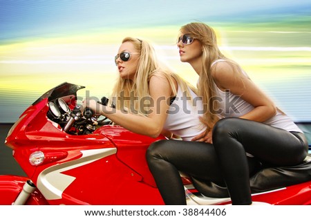 two pretty blonde woman on a big red motorcycle