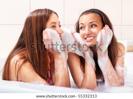 two tricksy beautiful women in jacuzzi with foam on hands