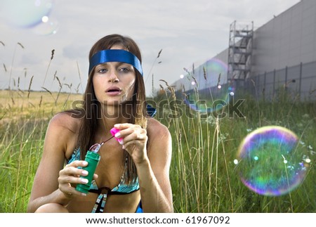 wistful young woman blowing soap bubbles in summer day