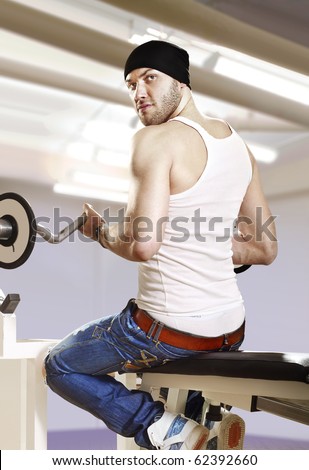 man makes exercises with bar in exercise room