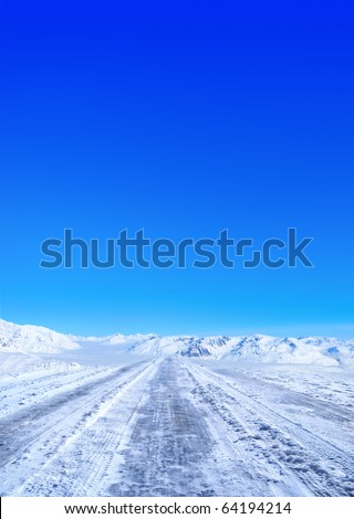 Snow covered road in winter with mountains in the distance