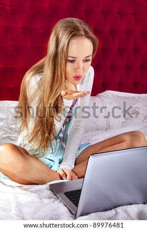 young enamored woman on the bed with laptop