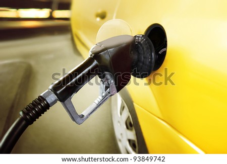 yellow car at gas station being filled with fuel