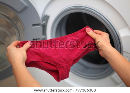 women\'s shorts in hands of woman who is going to do laundry it in washing machine