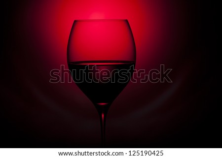 glass of red wine is on the red and black background