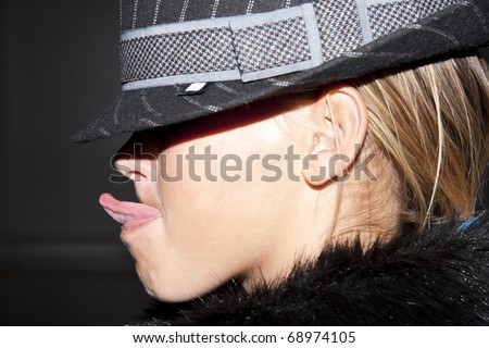 girl in a hat closing eyes also puts out tongue