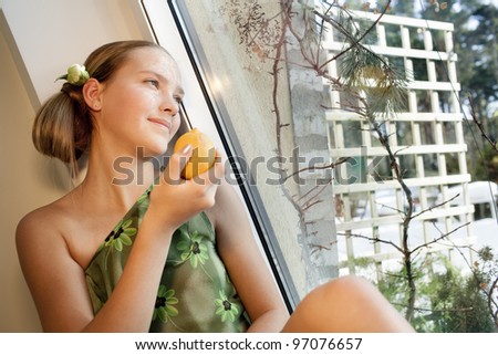 beautiful girl with green eyes is near the window and holds lemon,focus on left eye (close to window)