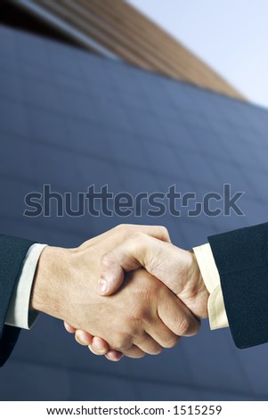 Two business man shaking hands in front of a modern building, nice light and depth of field.
