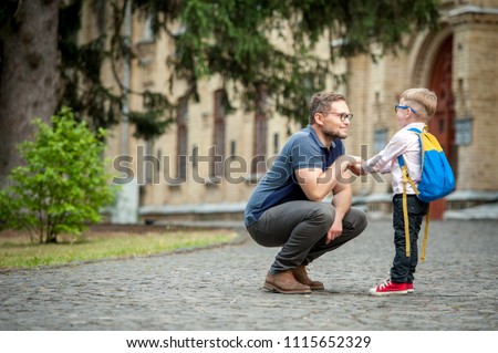 Back to school.  Happy father and son go to elementary school. Parent taking child to primary school. Pupil go study with backpack. Beginning of lessons.  First day of fall.